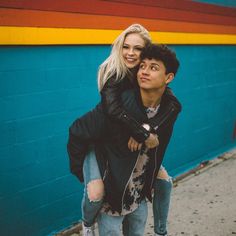 a man carrying a woman on his back in front of a blue and yellow wall