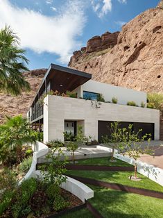 an image of a modern house in the mountains with palm trees and shrubs around it