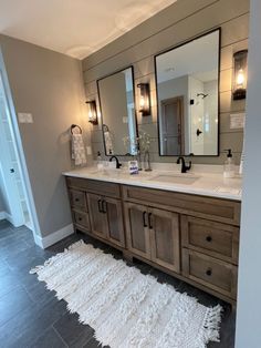 a large bathroom with double sinks and mirrors on the wall next to a white rug