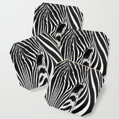 four black and white zebra coasters sitting on top of each other in front of a white background