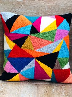 a multicolored pillow sitting on top of a wooden floor next to a wall