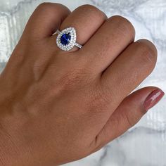 One of a kind pear shaped blue sapphire is surrounded by a double diamond halo - who can say no to that? The perfect pop of color for when you decide to pop the question Great as an engagement ring or anniversary present! Who wouldn't love a diamond halo ring with a blue sapphire center stone? Ever since Princess Di's famous engagement ring, women all over the world have discovered the beauty of blue sapphires. We love this ring especially for sparkling double diamond halo. It's a very special r Sapphire Teardrop Jewelry With Halo Setting, Blue Pear-shaped Sapphire Ring With Cubic Zirconia, Teardrop Sapphire Ring With Diamond, Teardrop Sapphire Jewelry With Halo Setting, Fine Jewelry Pear-shaped Sapphire Ring With Halo Setting, Pear-shaped Sapphire Ring With Halo Setting, Sapphire Pear-shaped Rings With Halo Setting, Teardrop Blue Sapphire Ring With Diamond, Pear-shaped Blue Diamond Ring Gift