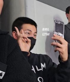 a man wearing a face mask holding up a cell phone