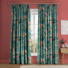 a living room with pink walls and blue floral curtains on the windowsill, along with a white rug