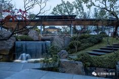 an outdoor area with rocks, water and trees in the foreground is lit up at night