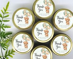 four baby shower favors in gold tins with teddy bears on them and thank you