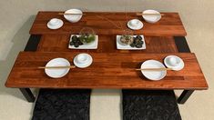 a wooden table topped with white plates and bowls