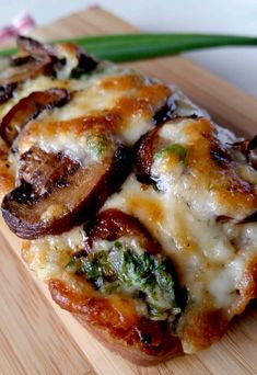 a piece of pizza sitting on top of a wooden cutting board next to green onions