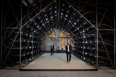 two men are walking down the runway in front of some metal scaffoldings