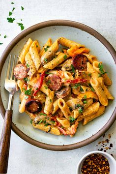 one pot creamy cajun sausage pasta in a white bowl with a fork on the side