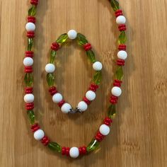 This 2 Piece Handmade Set Is A Beaded Necklace And A Stretch Bracelet. The Necklace Is 22” Long With A 2 1/4” Extension. The Bracelet Is 7.5” With Out Ant Stretch. The Beads Are Strung On A 1mm Elastic Cord. The Colors Are White, Red And Green. The White Beads Are 10 Mm Ceramic Round Beads. The Red Beads Are 6mm Acrylic Beads. The Green Beads Are 10mm Twist Glass Beads. Festive Glamorous One-Of-A-Kind Statement Casual Wear Christmas Winter Summer Colorful Handmade By Me White Beaded Christmas Jewelry, White Adjustable Jewelry For Christmas, White Adjustable Necklace For Christmas, White Christmas Jewelry With Colorful Beads, Hand-strung Red Round Bead Jewelry, Red Hand-strung Round Bead Jewelry, Red Hand-strung Beaded Necklace, Red Multi-strand Necklace With Wooden Beads, Boho Choker Necklace