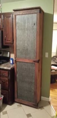 an old metal door in the corner of a kitchen with wood cabinets and tile flooring