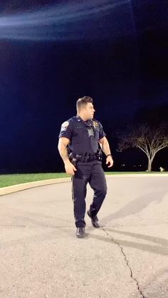 a police officer standing in the middle of a street at night with his hand on his hip