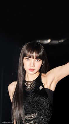 a woman with long black hair and bangs posing for the camera at a fashion show