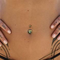 a woman's stomach with tattoos and piercings on her belly, holding a ring