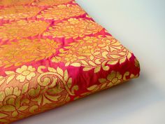 a red and gold brocaded fabric on a white surface