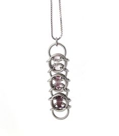 This lovely chain maille pendant showcases a beautiful blend of pink and purples for a very feminine touch to any jewelry collection!  This glass pendant was crafted out of stainless steel jump rings, as well as glass rings in three soft colors - light rose pink, light purple, and a darker amethyst purple. It measures approximately 2 1/4 inches long and 5/8 inch wide.  Stainless steel is a very durable material that resists tarnishing. It is very strong and therefore unlikely to bend out of shap Stainless Steel Jewelry Making Jump Rings, Pink Wire Wrapped Metal Jewelry, Nickel-free Pink Stainless Steel Jewelry, Pink Nickel-free Stainless Steel Jewelry, Spiral Pink Jewelry For Gifts, Pink Spiral Jewelry For Gifts, Chainmaille Jewelry, Chain Maille Jewelry, Rainbow Jewelry