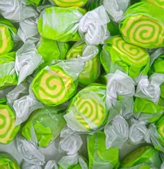 green and white candies with yellow swirls on them, all in plastic wrappers