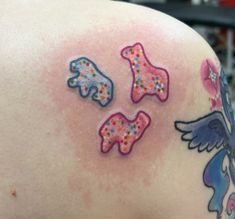 the back of a woman's shoulder with colorful tattoos on her left arm and chest