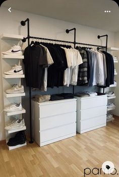 an organized closet with white drawers and black clothes hanging on the rail, along with shoes