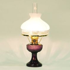 a purple lamp with a white shade on it's top sitting on a table