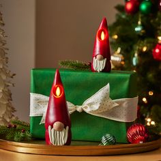 two small christmas candles sitting on top of a green present