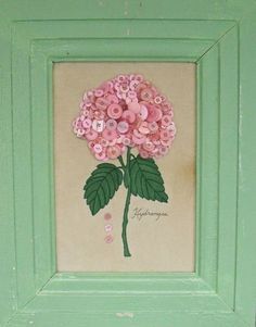 a pink flower with green leaves and buttons in a frame on the wall next to a toilet