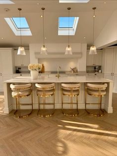 a kitchen with an island and four stools in the center, along with two skylights