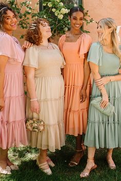 three women standing next to each other in dresses