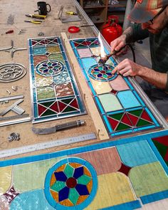 a man working on stained glass in a shop with tools and other items around him