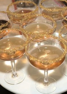 several glasses filled with different types of drinks on a white plate and black table cloth