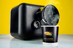 a coffee cup with steam coming out of it next to a black ice cream dispenser