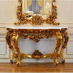 an ornate gold console table with a mirror on the wall above it and wood flooring