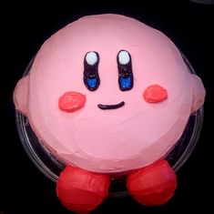 a pink cake with two eyes and one nose on it's face, sitting in front of a black background