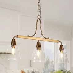 a kitchen light with three lights hanging from it's center and two clear glass shades