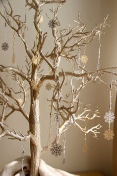 a tree with ornaments hanging from it's branches in front of a white wall