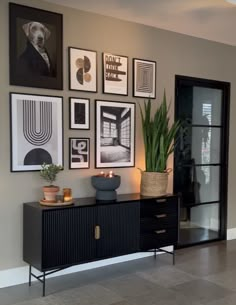 a living room with pictures on the wall and a potted plant in front of it