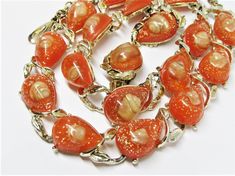 "A classic vintage 1950's confetti Lucite jewelry set with embedded seashells. This fabulous set includes a choker necklace, link bracelet, and clip on earrings. They feature coral colored Lucite teardrops with embedded golden confetti and creamy iridescent seashell. The jewelry has a shiny gold plating with a tiny curling leaf motif. A beautiful, high quality jewelry set that would be perfect for summer at the beach. -Age: 1950's -Material(s): Confetti Lucite, embedded seashells and gold plated Vintage Orange Jewelry For Party, Retro Orange Jewelry For Party, Lucite Jewelry, Vintage Jewelry Sets, Seashell Jewelry, Coral Color, High Quality Jewelry, Cute Earrings, Link Bracelets