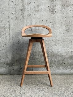 a wooden stool sitting in front of a concrete wall