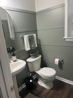 a white toilet sitting next to a sink in a bathroom under a window with blinds