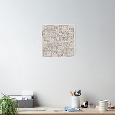 a desk with a plant and some books on it next to a wall mounted poster