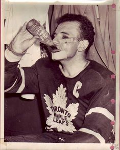 an old black and white photo of a man drinking from a bottle