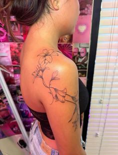 the back of a woman's shoulder with flowers tattooed on her left arm and chest