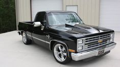 a black pickup truck parked in front of a garage with its hood up and the hood down