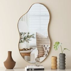 a mirror sitting on top of a table next to vases and a plant in a vase