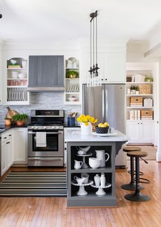 a kitchen with stainless steel appliances and white cabinets is pictured in this image, there are yellow flowers on the counter