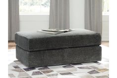 a grey ottoman sitting on top of a white rug