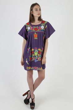 "Vintage traditional Mexican Puebla mini dress. Draped shift fit with fluttery cap sleeves. Purple cotton with bright floral embroidery. size estimate: M/L shoulders: 19.5\" bust: 44\" waist: - hips: 56\" total length: 33.5\" * Visit the shop * https://www.etsy.com/shop/americanarchive Model is 5'10\" Accessories not included." Multicolor Mini Dress With Floral Embroidery, Embroidered Flutter Sleeve Summer Dress, Summer Embroidered Flutter Sleeve Dress, Multicolor Embroidered Floral Print Short Sleeve Dress, Short Sleeve Floral Print Dress With Multicolor Embroidery, Spring Purple Embroidered Dress With Floral Detail, Multicolor Embroidered Dress With Short Sleeves, Purple Embroidered Dress For Summer, Multicolor Floral Embroidered Short Sleeve Dress