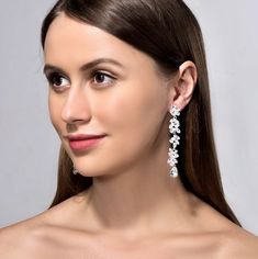 a woman with long hair wearing earrings on her head and looking off to the side