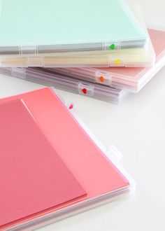 three binders are stacked on top of each other, with colored paper attached to them